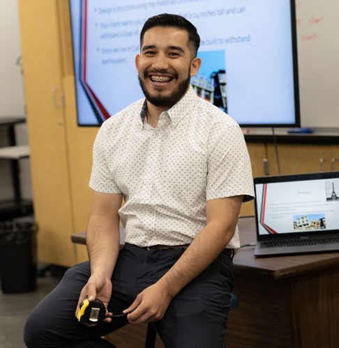 Staff Engineer Jesus Hernandez smiling in front of a PowerPoint presentation
