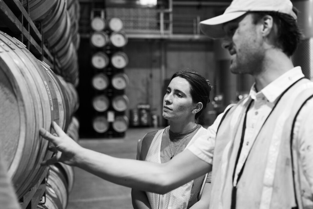 People discussing wine barrels black and white